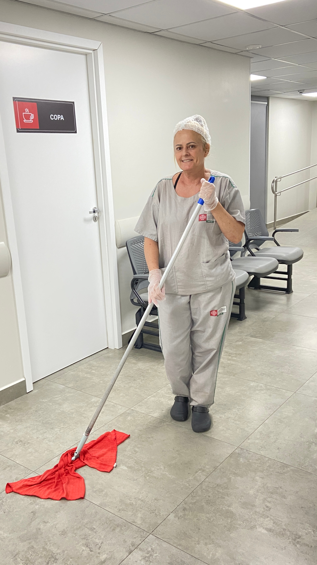 Colaboradora SLG sorrindo durante limpeza de corredor