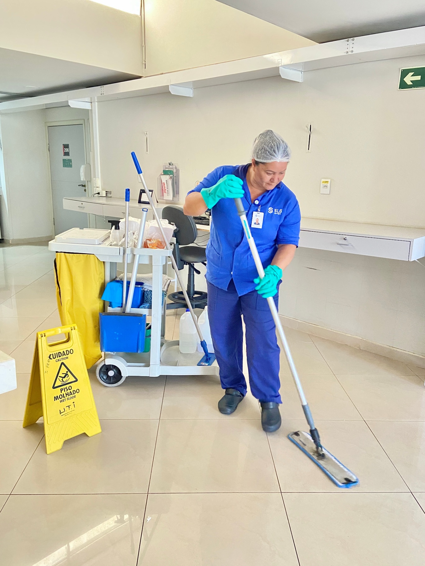 Colaboradora SLG higienizando piso de área comum com mop
