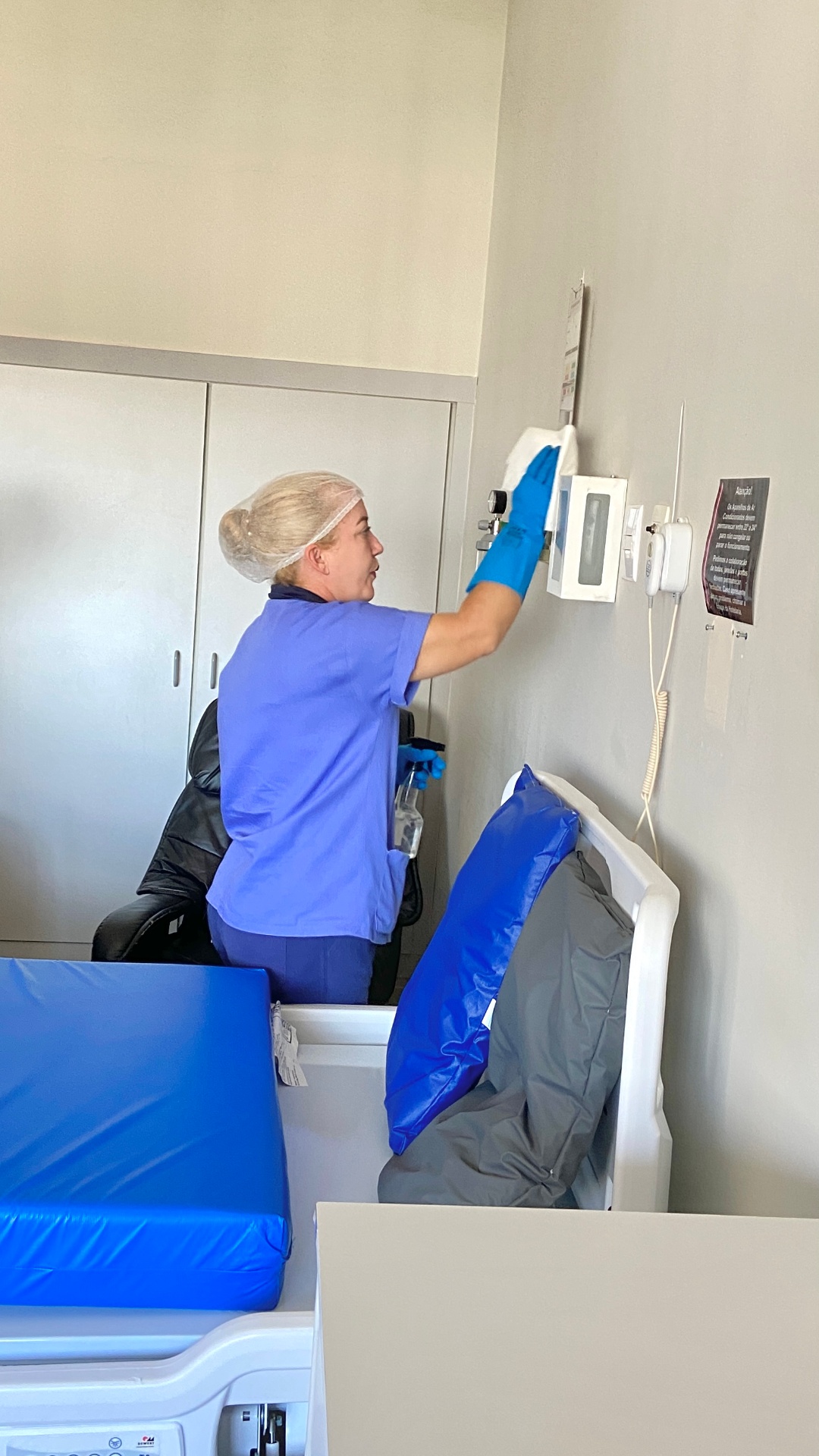 Profissional SLG higienizando painel de controle em quarto hospitalar